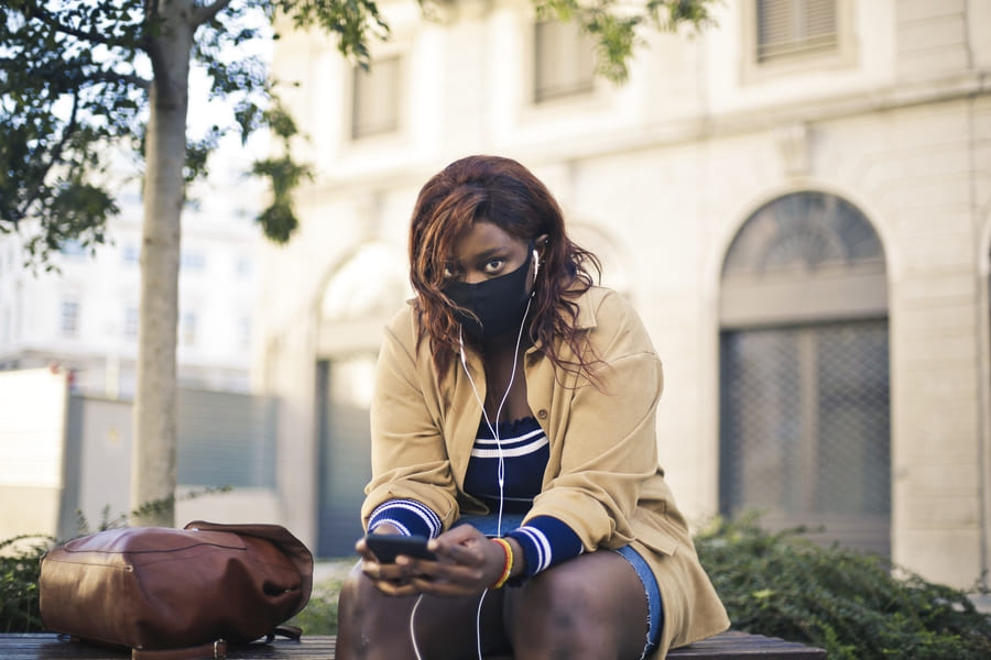 jeune femme avec masque assis sur un banc ecoute de la musique2