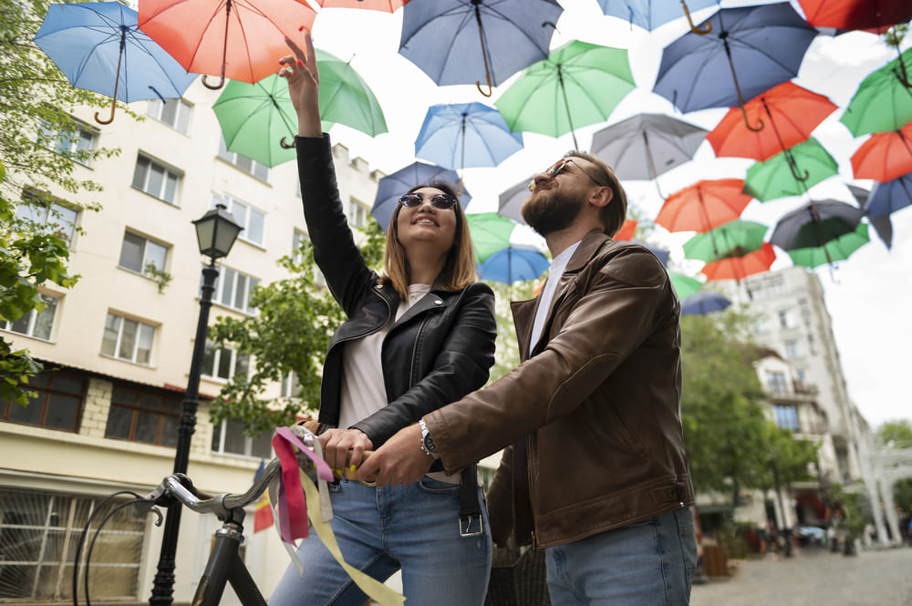 couple dans des vestes en cuir synthetique passant sous des parapluies colores a l
