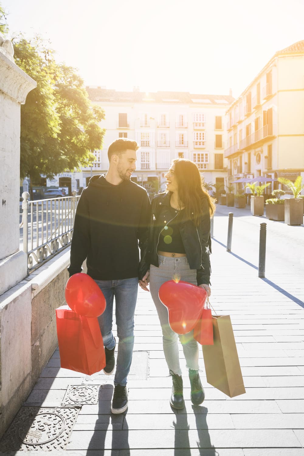 jeune homme avec des paquets et un ballon tenant par la main avec une dame souriante sur la rue11