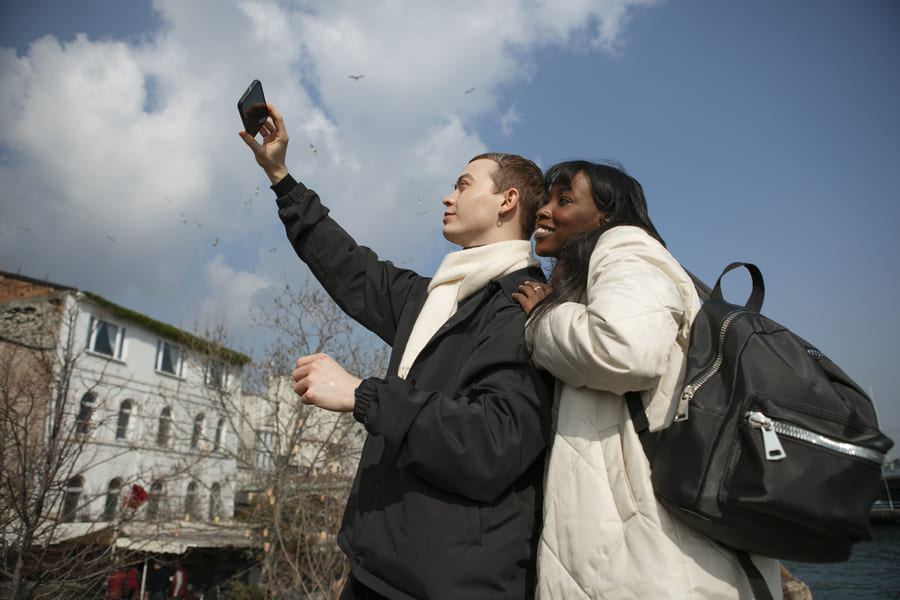 touristes masculins et feminins prenant un selfie a l exterieur avec leur smartphone1